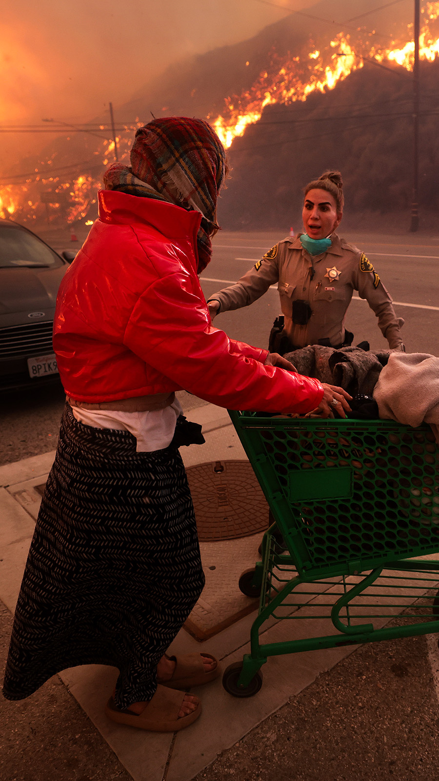 A homeless woman pushes her belongings along Pacific Coast Highway