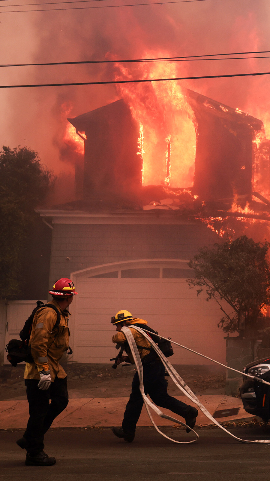 Firefighters battle a house fire off Bollinger Drive in Pacific Palisades