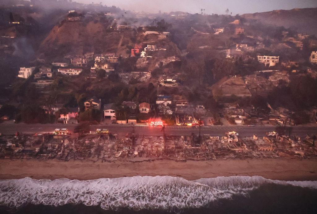 In an aerial view, destroyed homes are seen along the beach as the Palisades Fire continues to burn on January 09, 2025 in Malibu, California