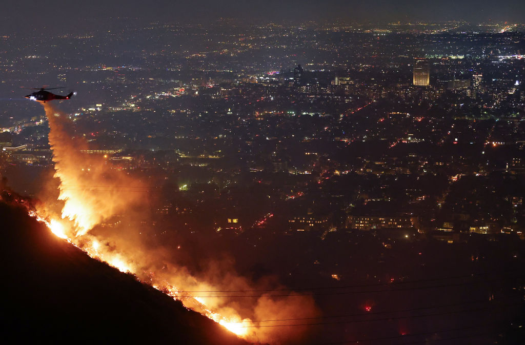 A firefighting helicopter drops water as the Sunset Fire burns in the Hollywood Hills on January 8, 2025 in Los Angeles, California