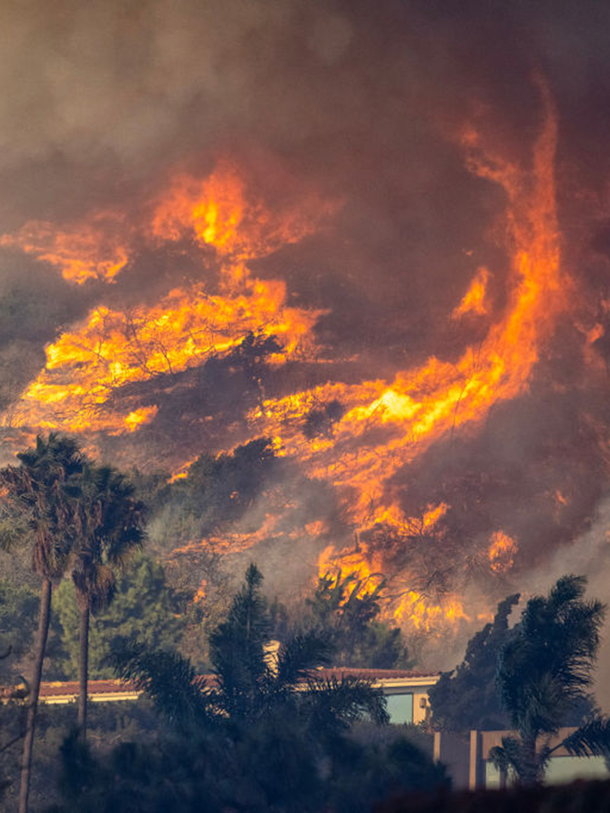 Winds whip up the fires in the brush of the hills near Pacific Palisades