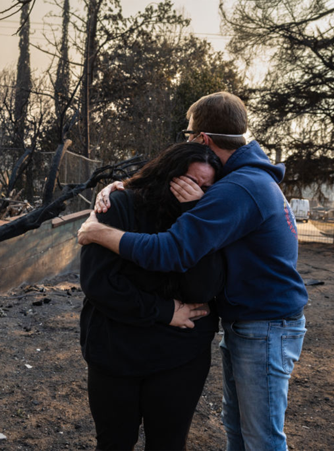 A man conforts his daughter on the charred ruins of their family home burned in the Eaton Fire in Altadena, California, January 9, 2025