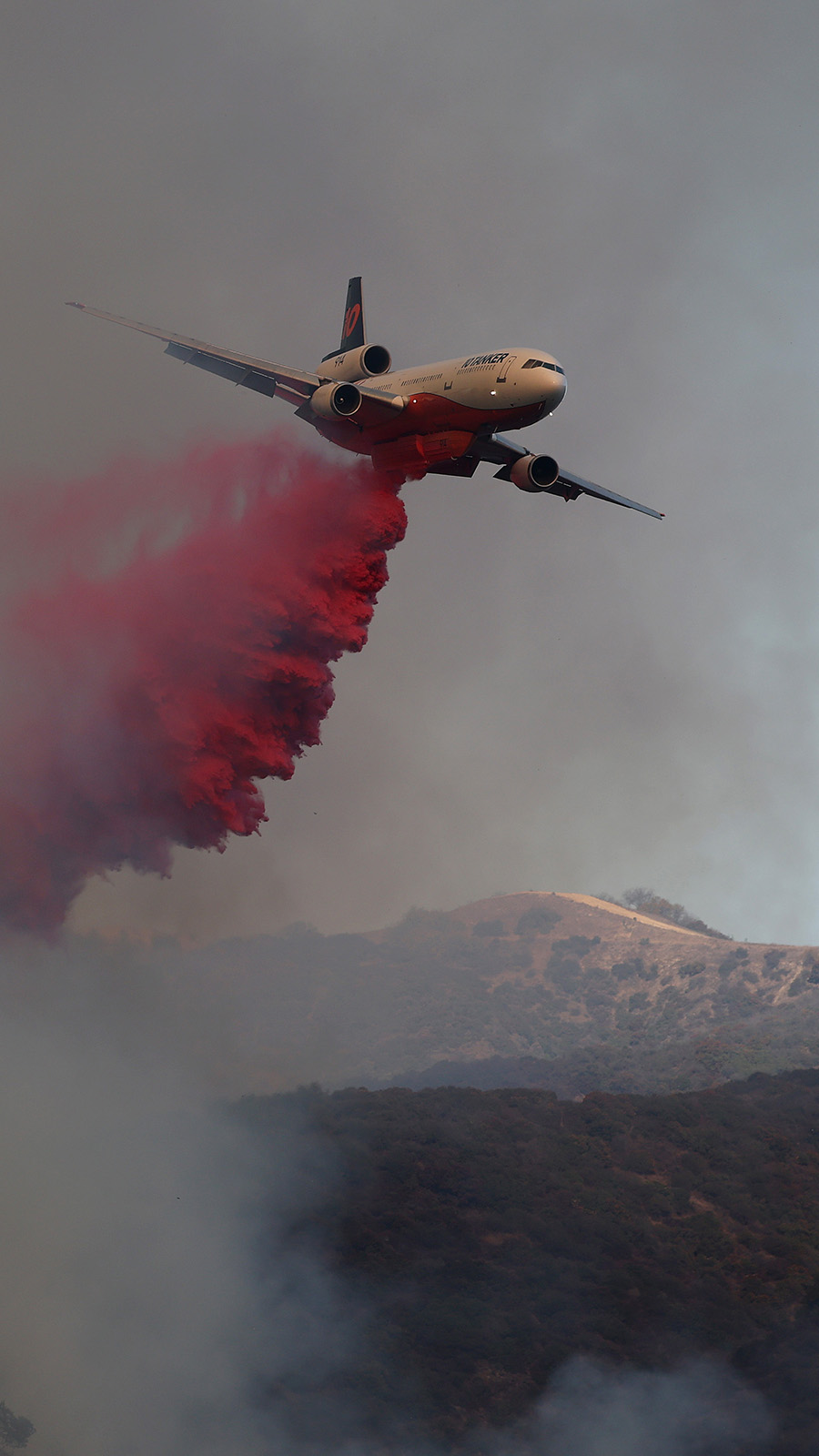 A firefighting aircraft drops retardant ahead of the Palisades Fire on January 11