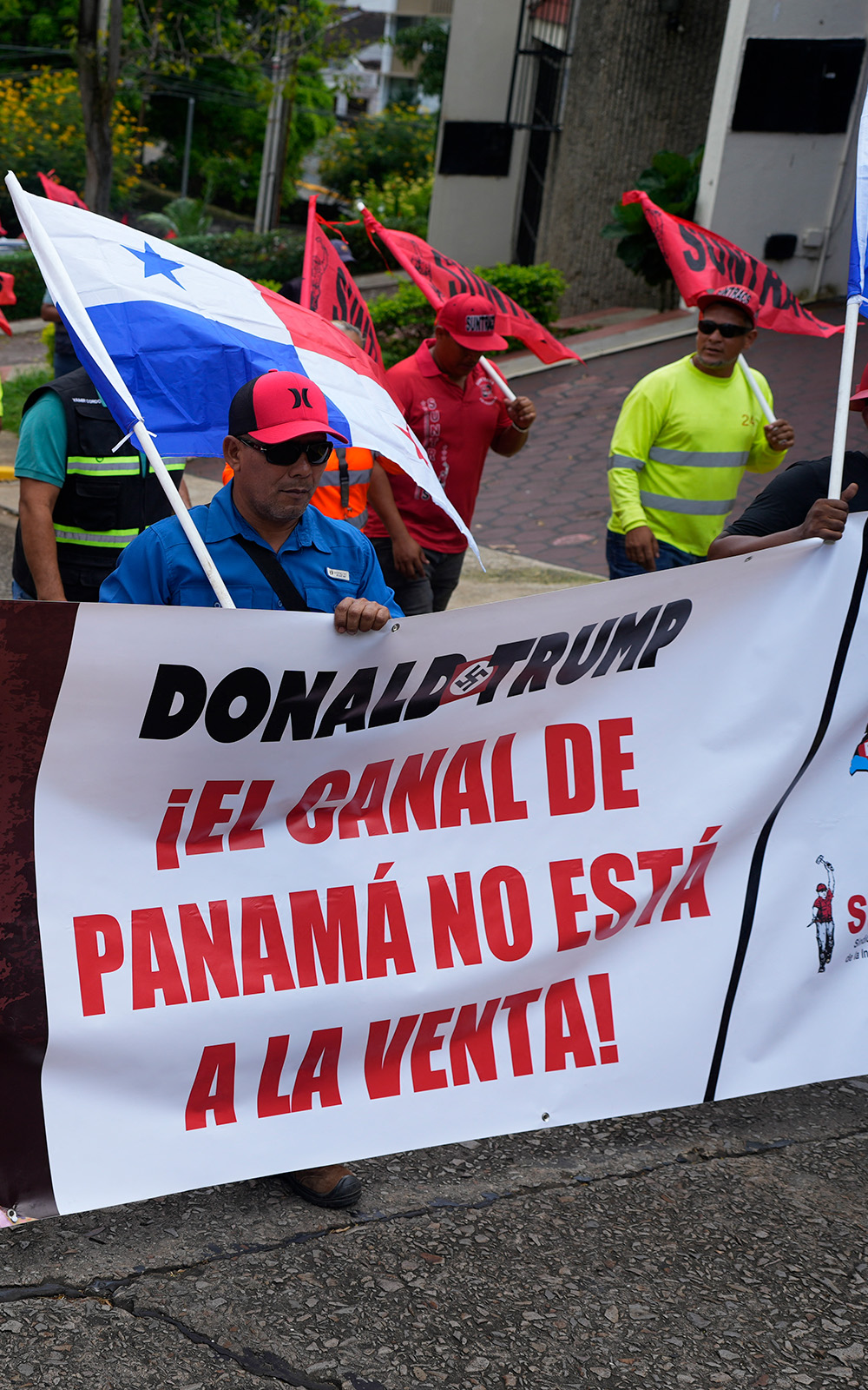 Protesters in Panama carry flags and a  banner that says the Panama Canal is not for sale