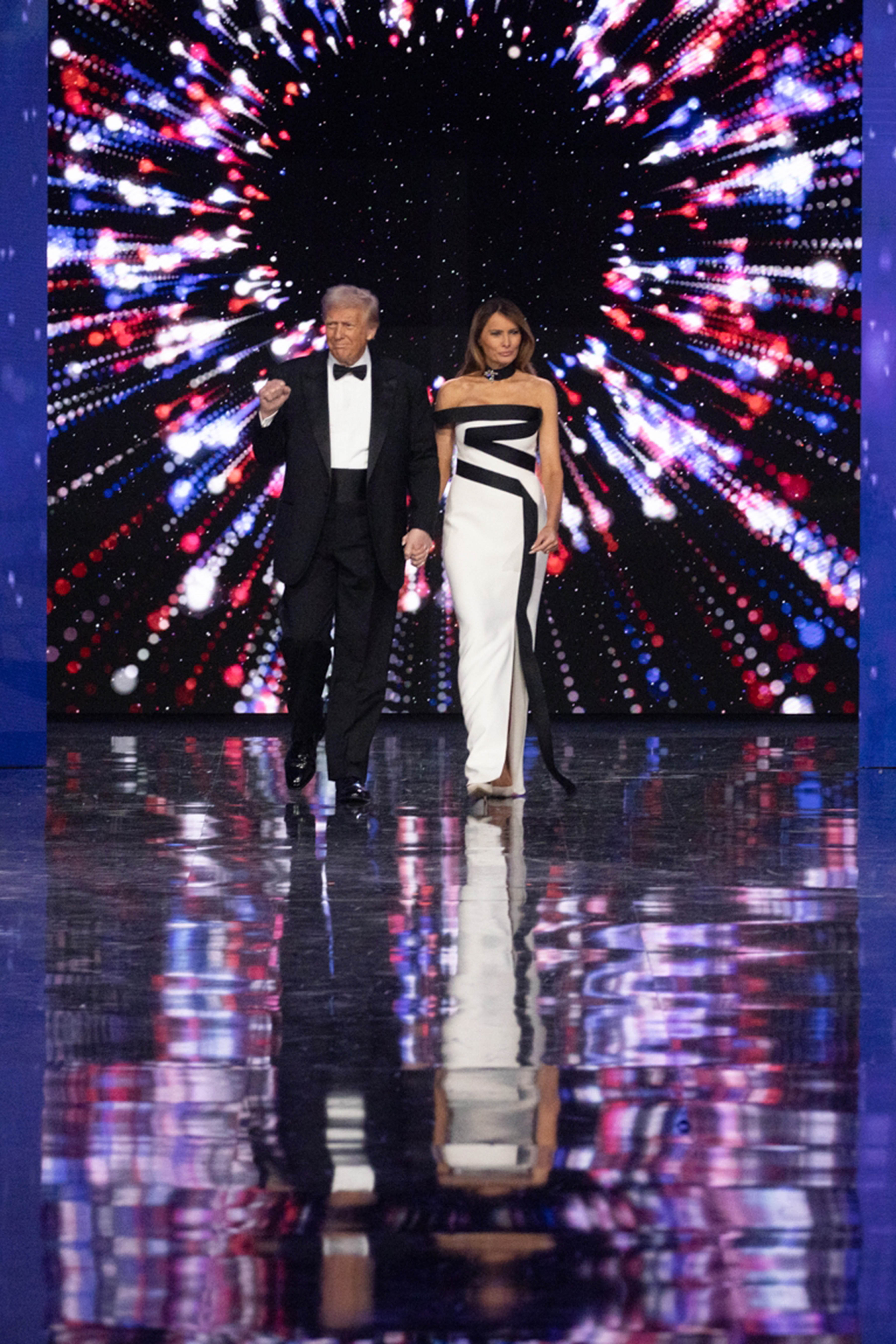 US President Donald Trump in a black tuxedo and First Lady Melania Trump in the full length white and black gown arrive at the Liberty Ball