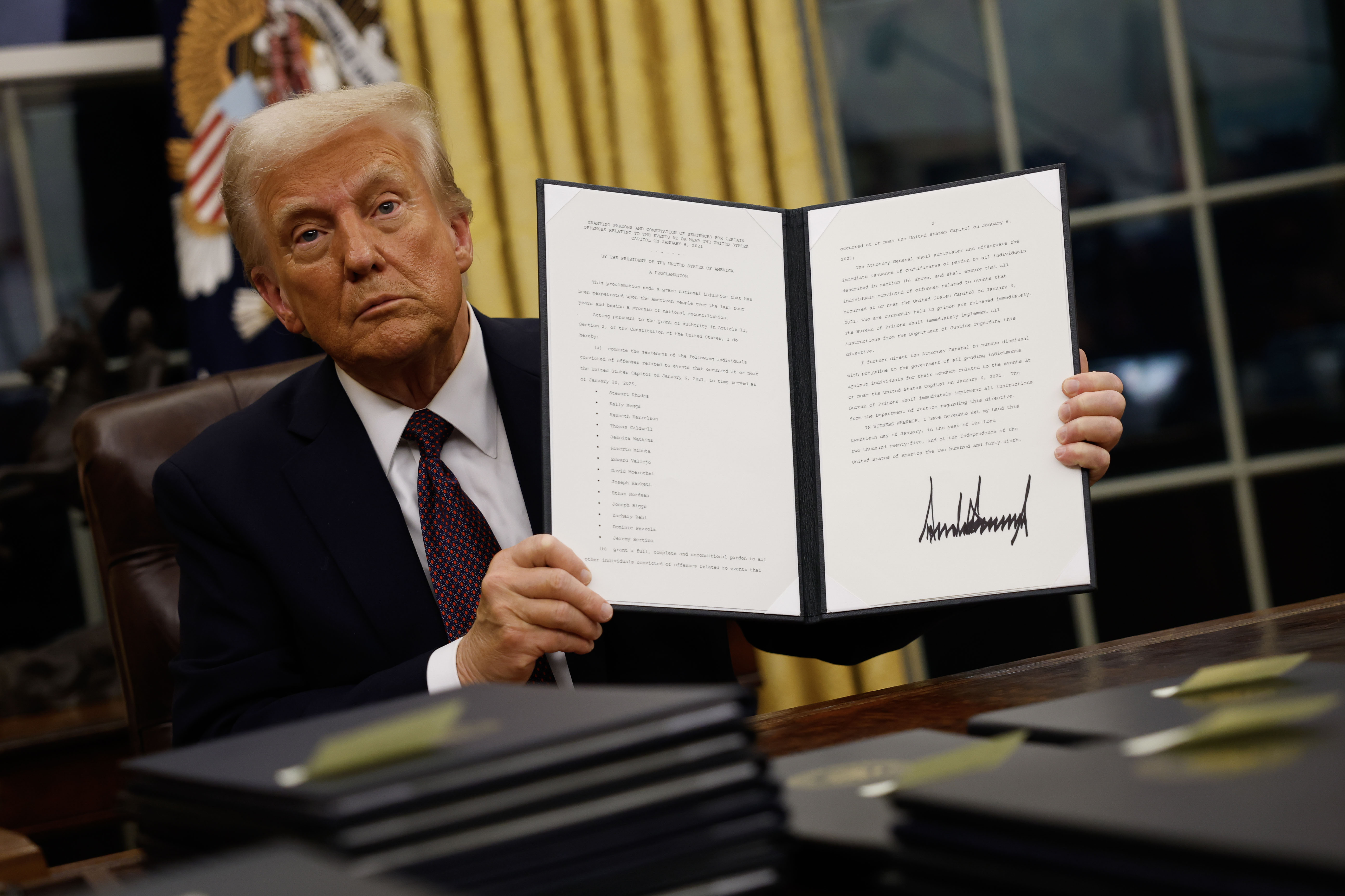 President Donald Trump holds up a signed executive order in the Oval Office