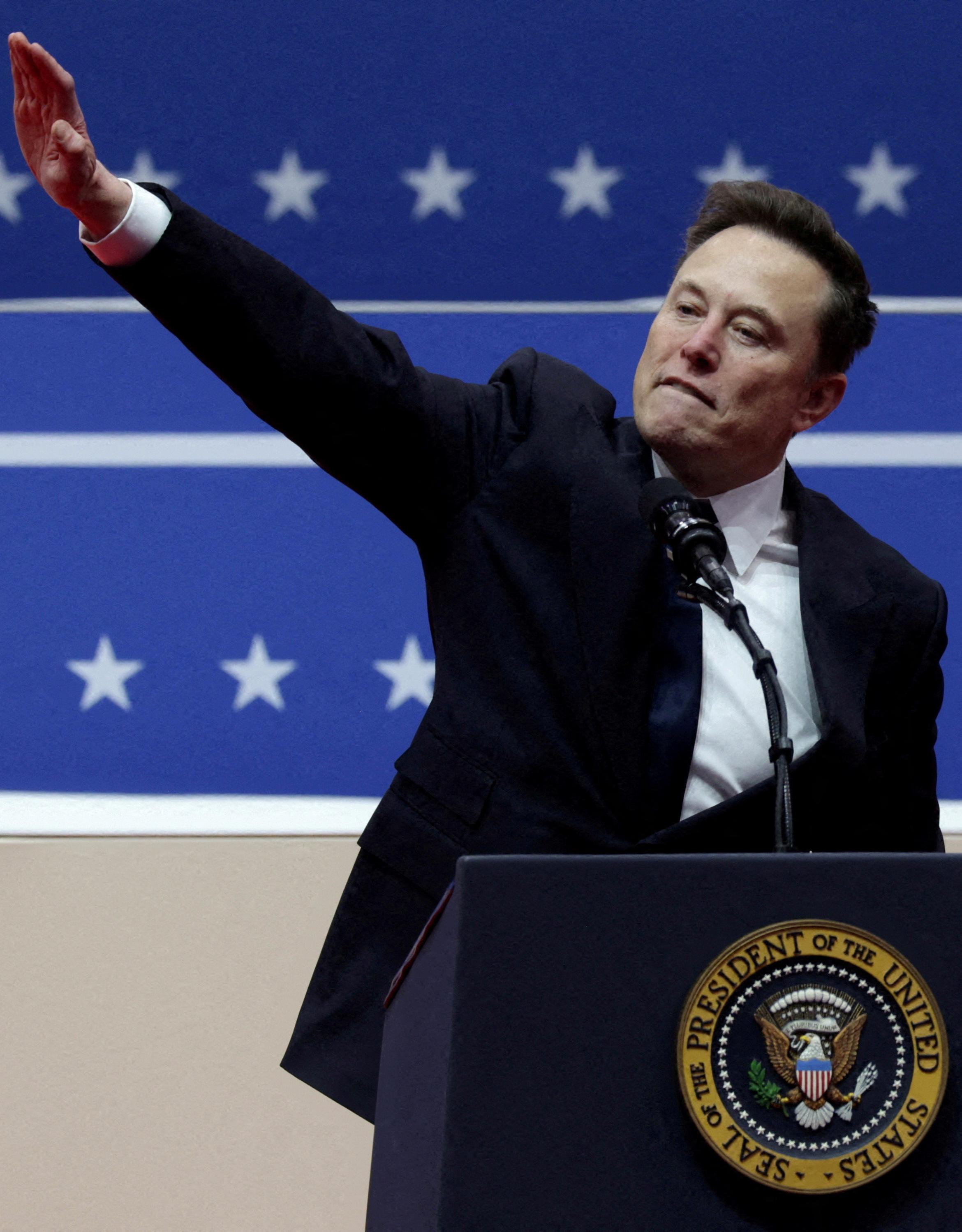 Elon Musk gestures at the podium inside the Capital One arena