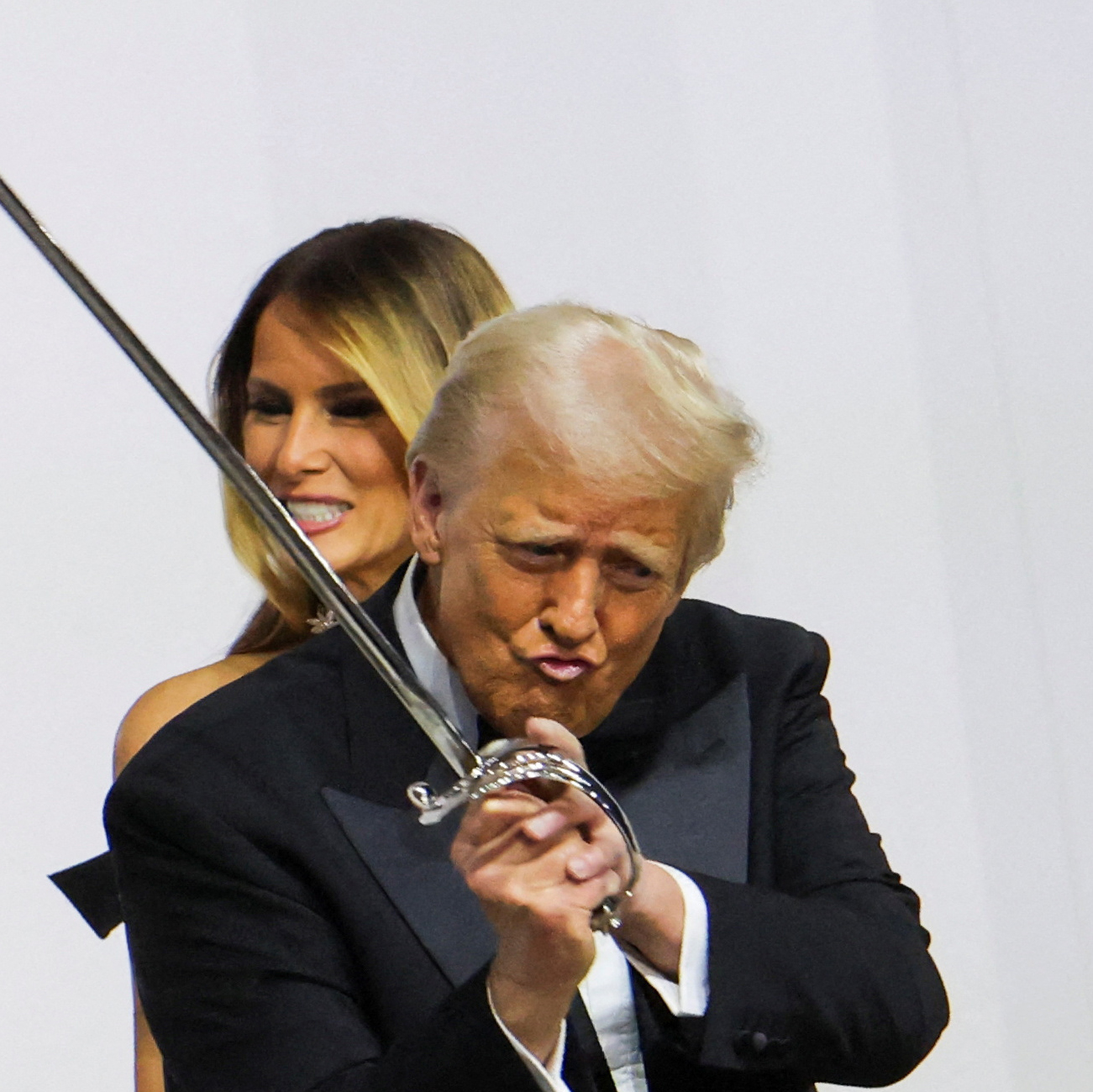 US President Donald Trump gestures while holding a sword, near Melania Trump