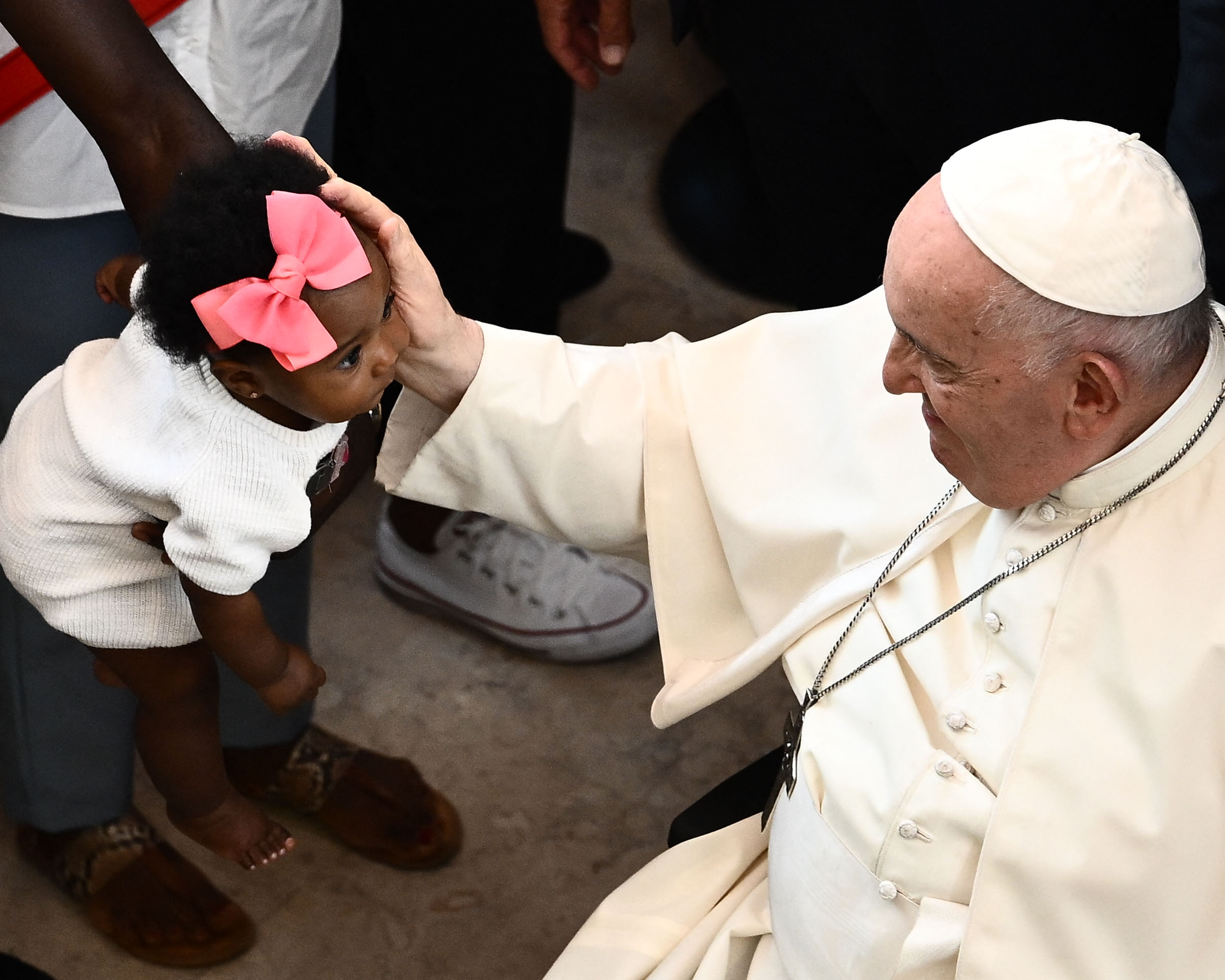 Pope Francis with his hand on a toddler's face during his visit to the Serafina parish social centre in Lisbon, on August 4, 2023