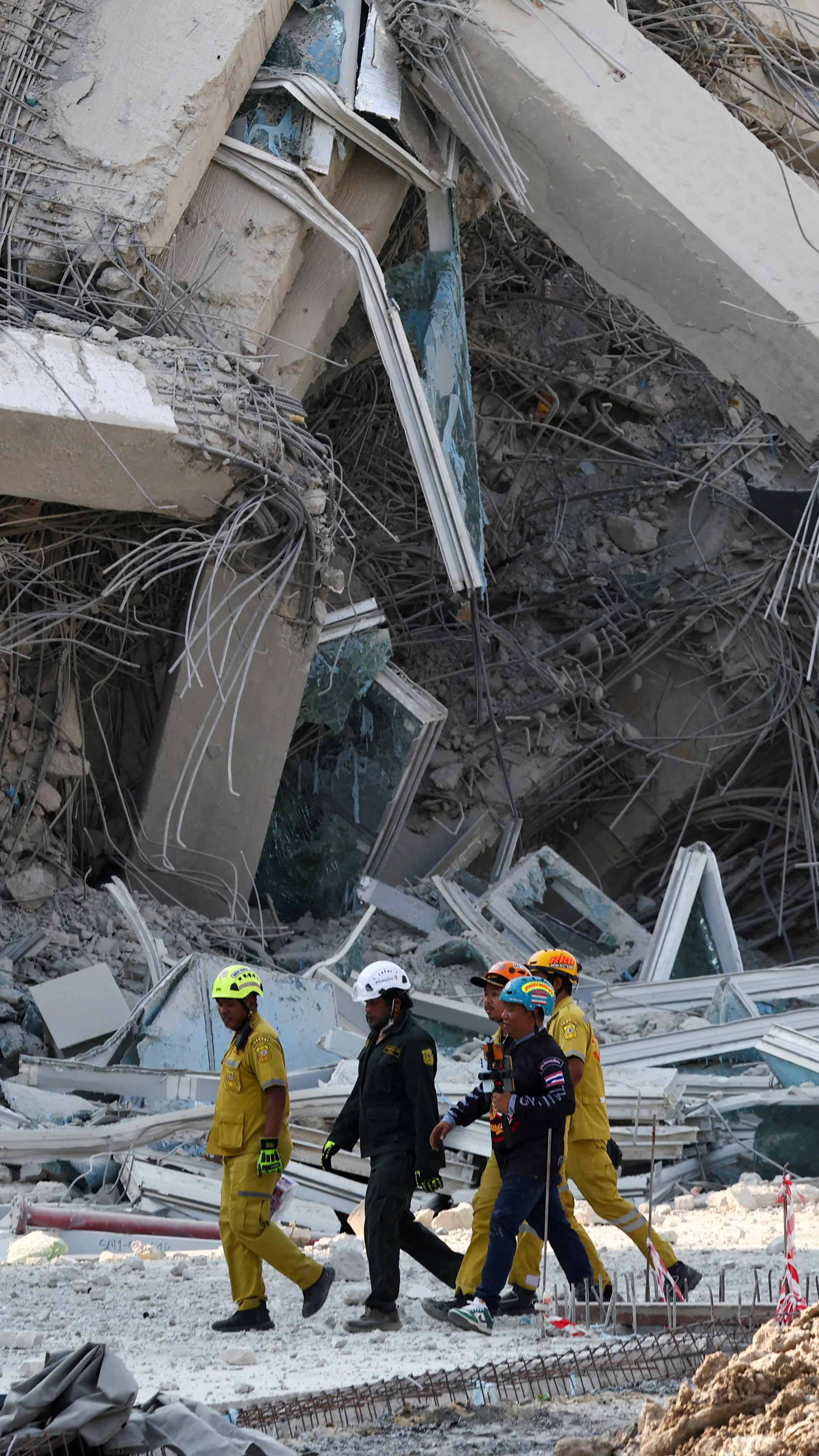 Rescue personnel walk near a building that collapsed in Bangkok after a strong earthquake