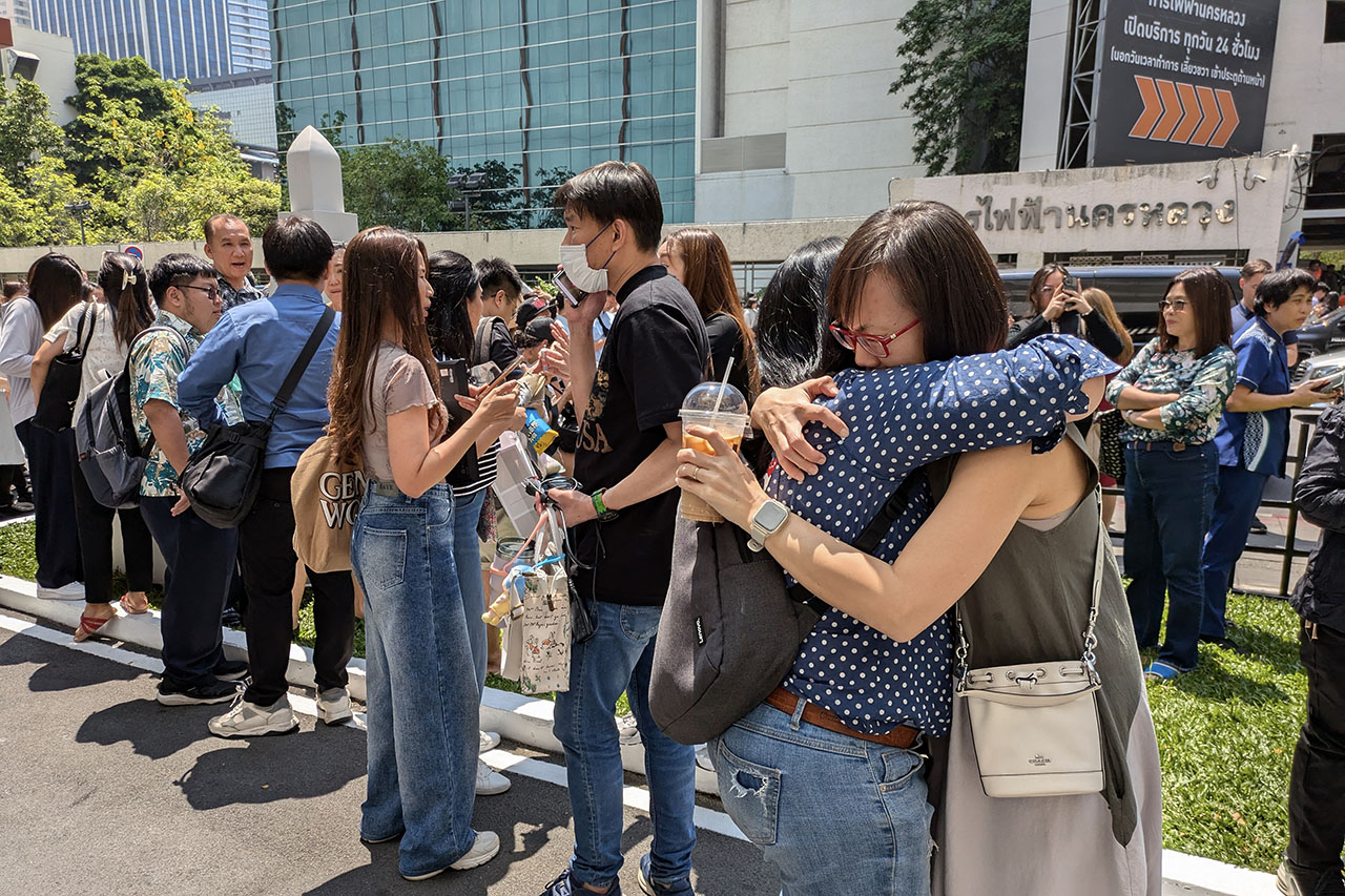 People stand outside an office building in Bangkok, Thailand on March 28, 2025 after an earthquake