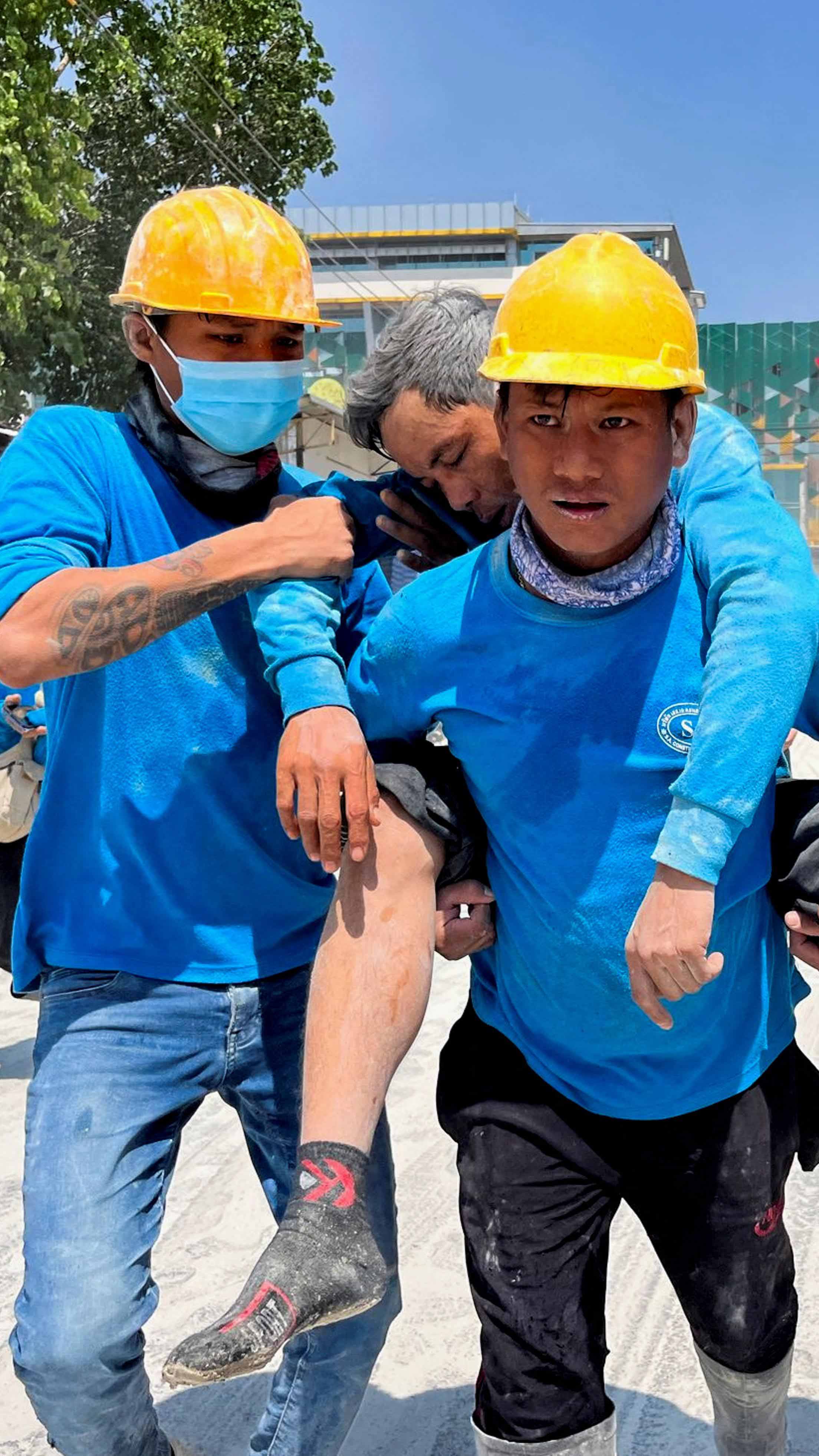 Workers carry an injured person near the site of a collapsed building in Bangkok, Thailand, after a strong earthquake