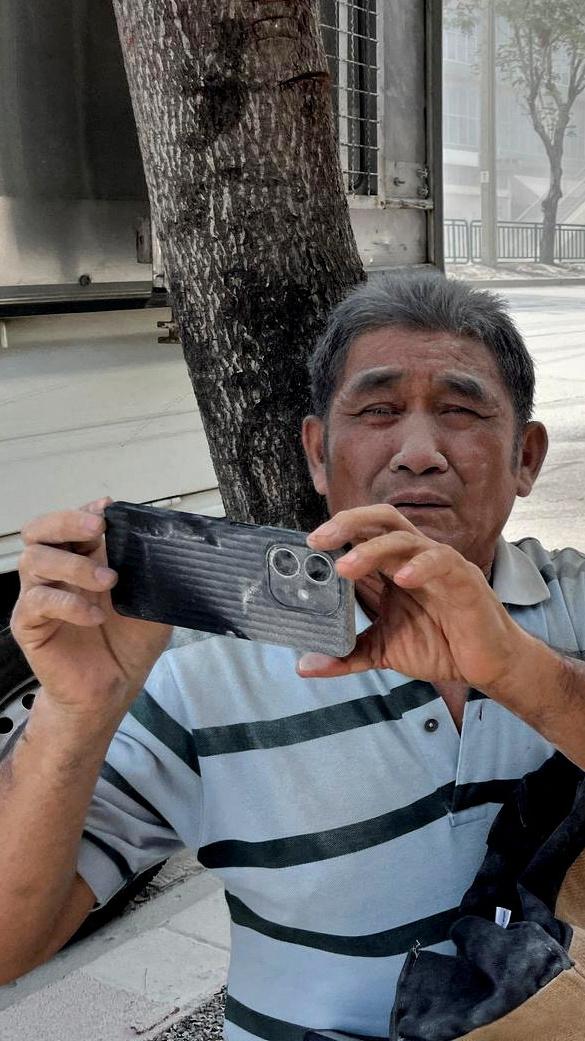 A man covered in dust uses his phone on a street in Bangkok, Thailand, after a strong earthquake