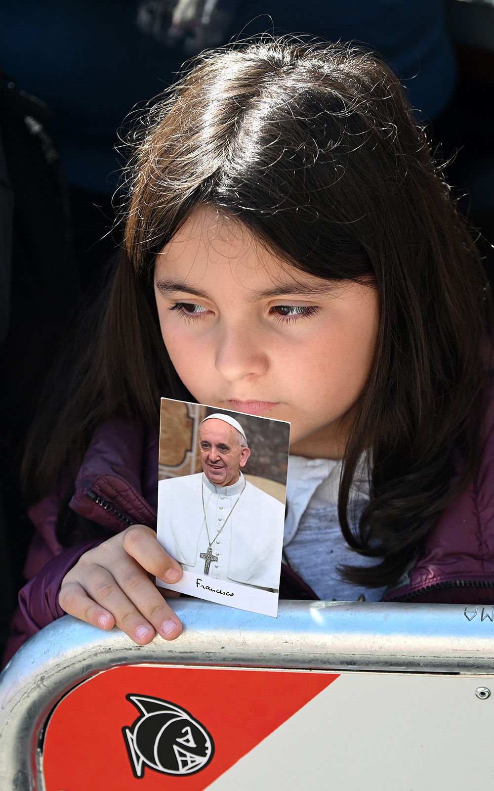A young girl holds a photo of late Pope Francis during the funeral