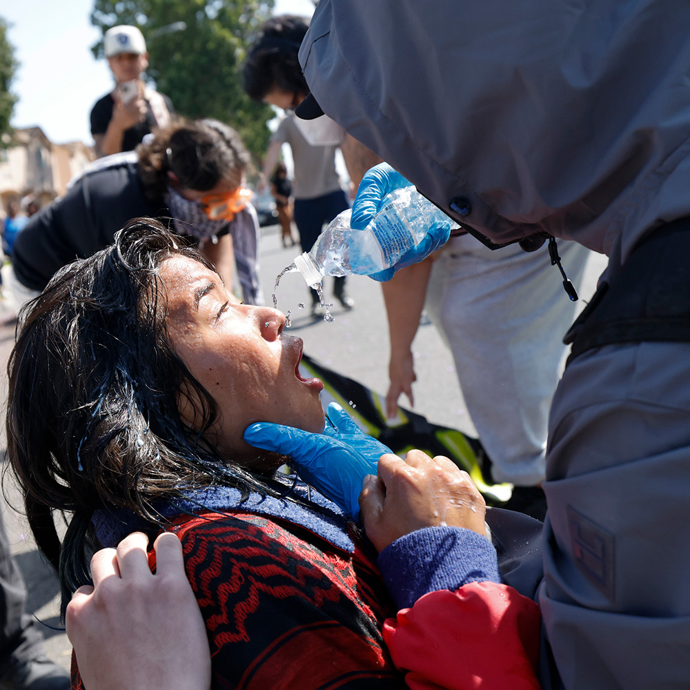 An anti-ICE protester gets tear gassed and is helped by fellow protesters on Hunsaker Ave