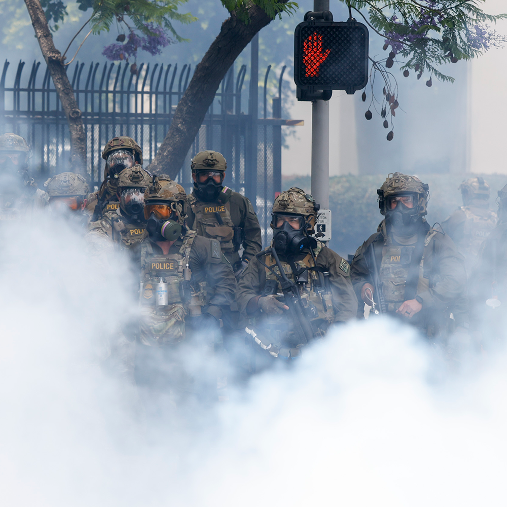 Immigration and Customs Enforcement officers stand guard behind clouds of tear gas on East Alondra Blvd