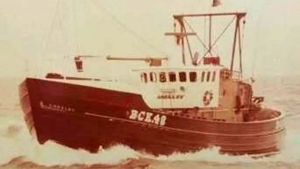 Old photo of fisherman on a fishing boat, wearing waterproof oils and a cap, the man - Jim Runcie - also has a cigarette in his mouth, sea and lots of seagulls in the background.