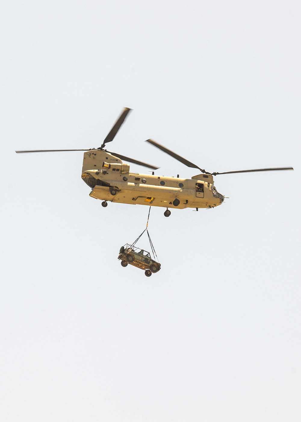 A helicopter transports a military vehicle over Fort Cavazos in Killeen, Texas