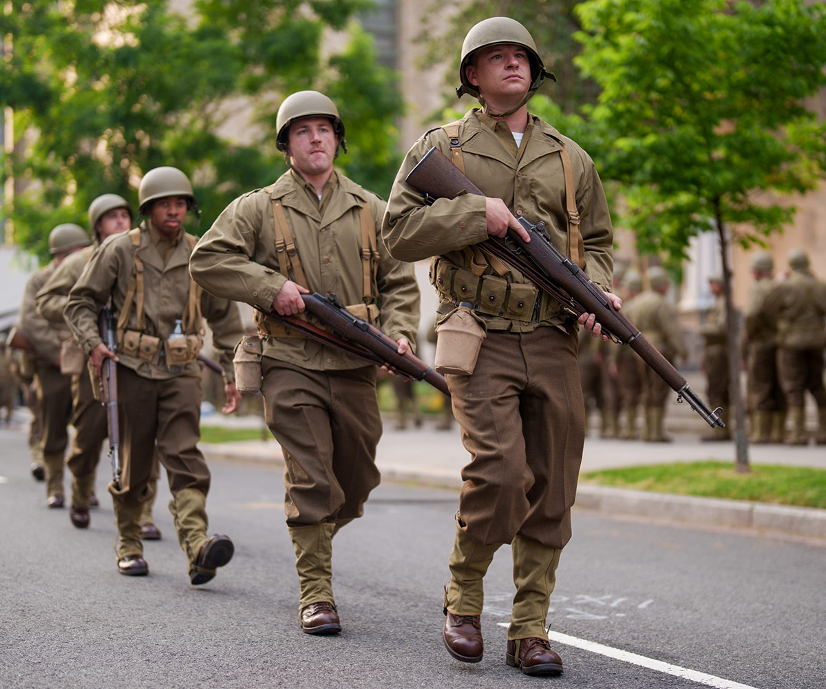 US Army soldiers dressed in uniforms from World War Two march along a road in Washington DC