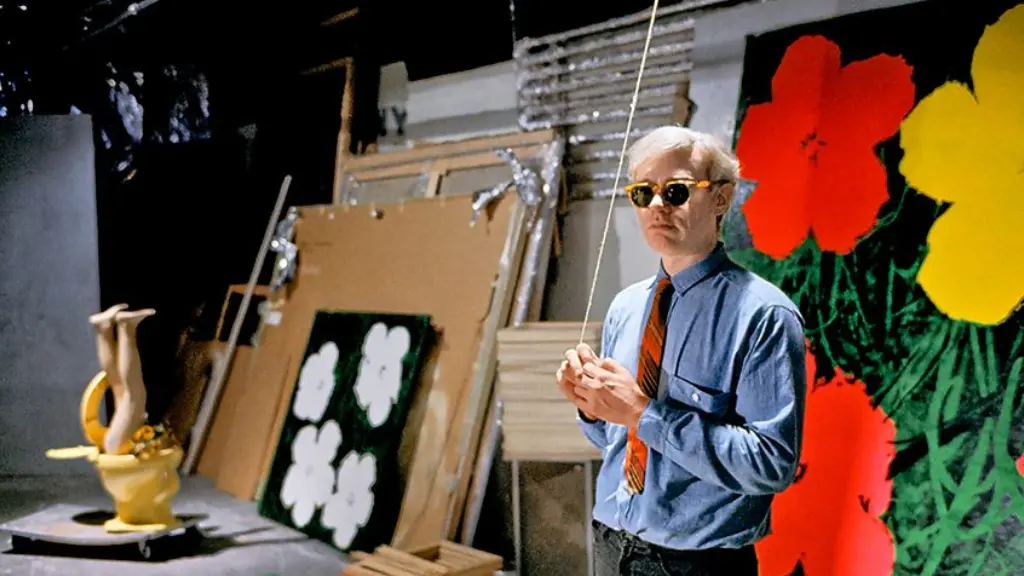 A black and white photo of Andy Warhol wearing sunglasses and leaning against a wall (Credit: Getty Images)