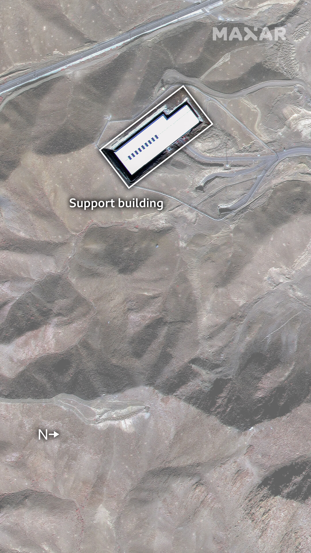 A satellite image of the Fordo site, showing some roads leading to the white support building and bare rock and earth