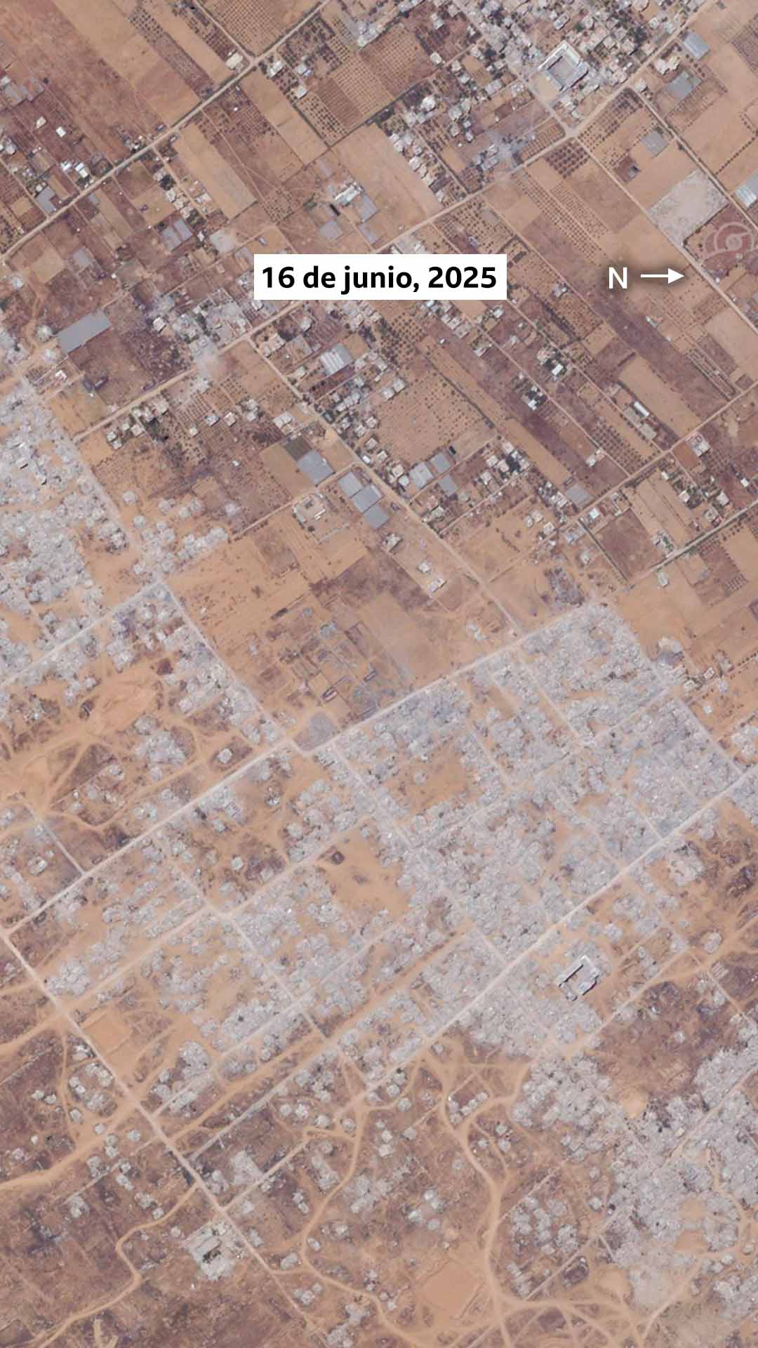 Imagen satelital de Khuza'a del 16 de junio de 2025. La imagen muestra que la mayoría de los edificios del asentamiento, los invernaderos y la mayor parte de la vegetación han sido destruidos.