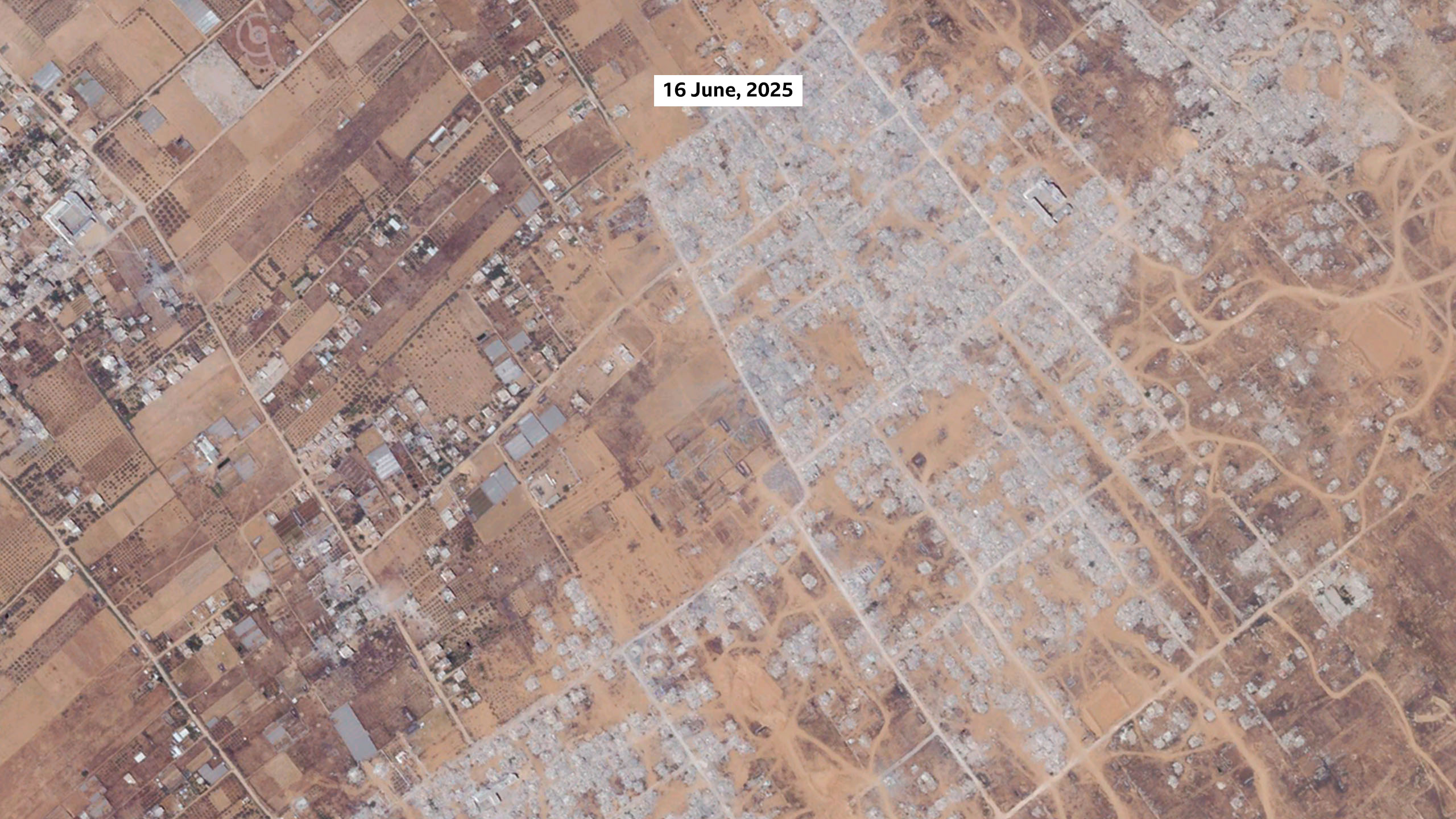 A satellite image of Khuza'a on 16 June, 2025. The image shows that most of the buildings in the settlement, the greenhouses, and most of the vegetation has been destroyed.