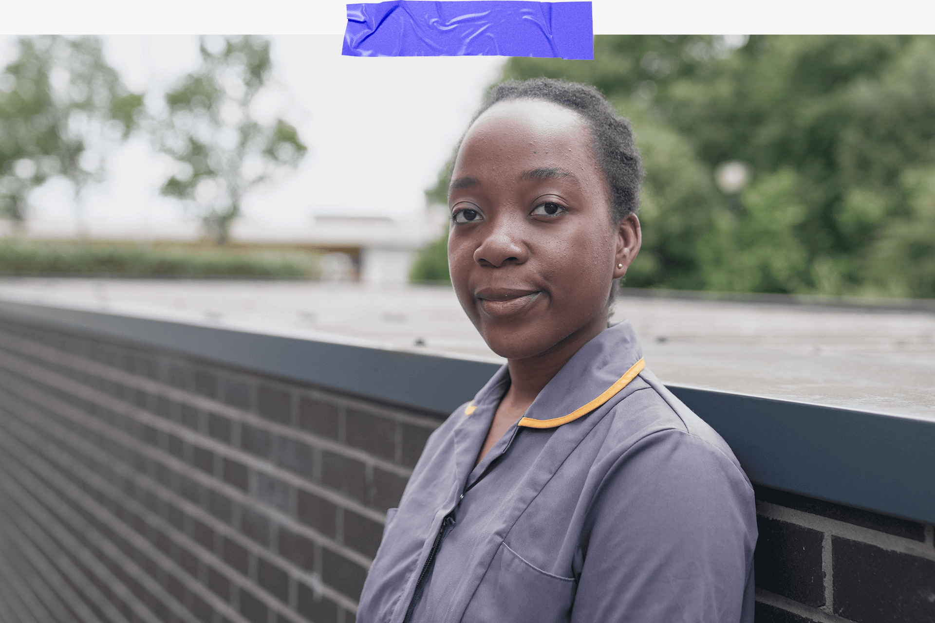 Halima wearing scrubs standing against a wall