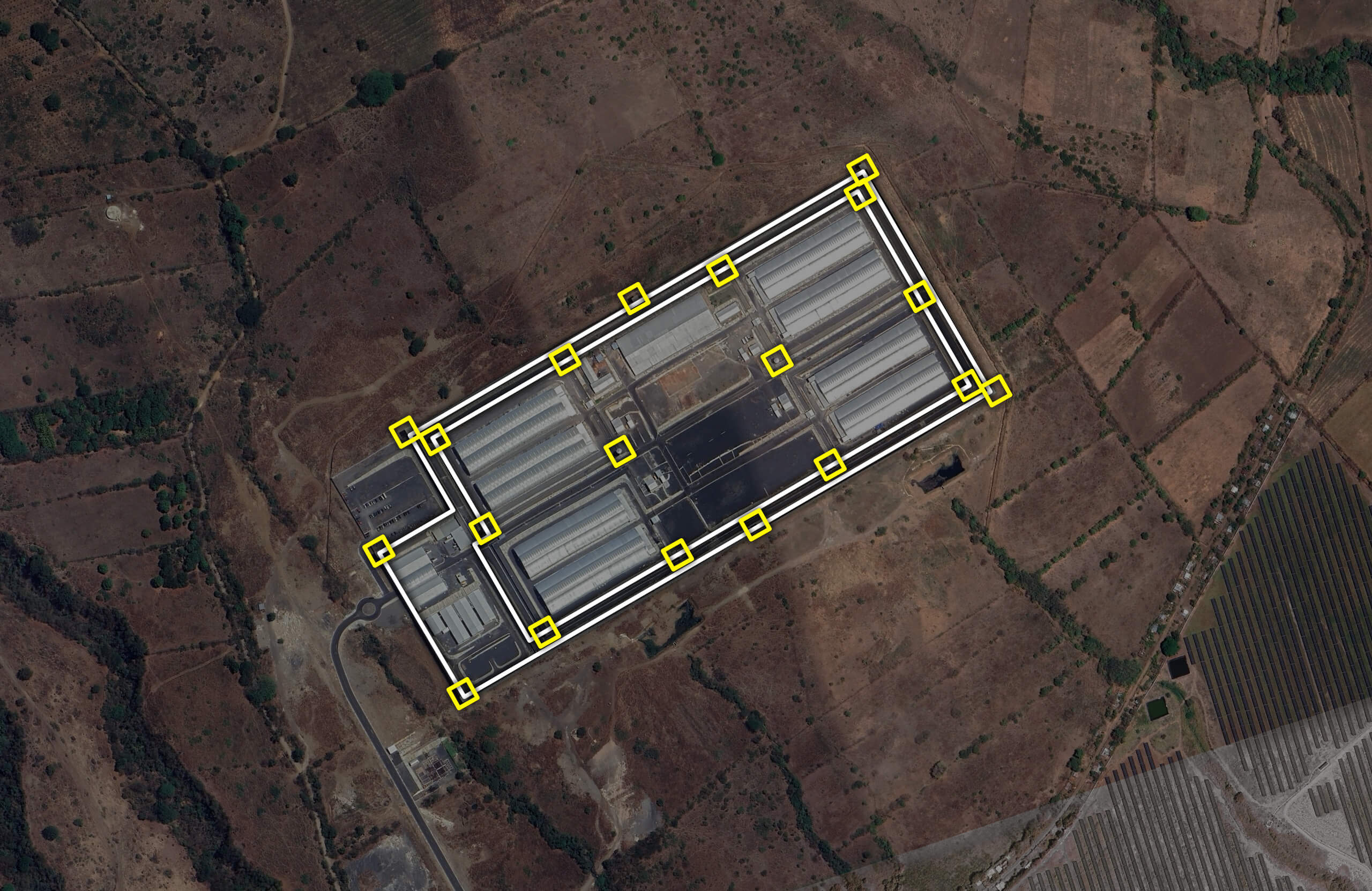 Aerial image of the Cecot prison with the perimeter walls highlighted in white lines and the watchtowers in yellow squares