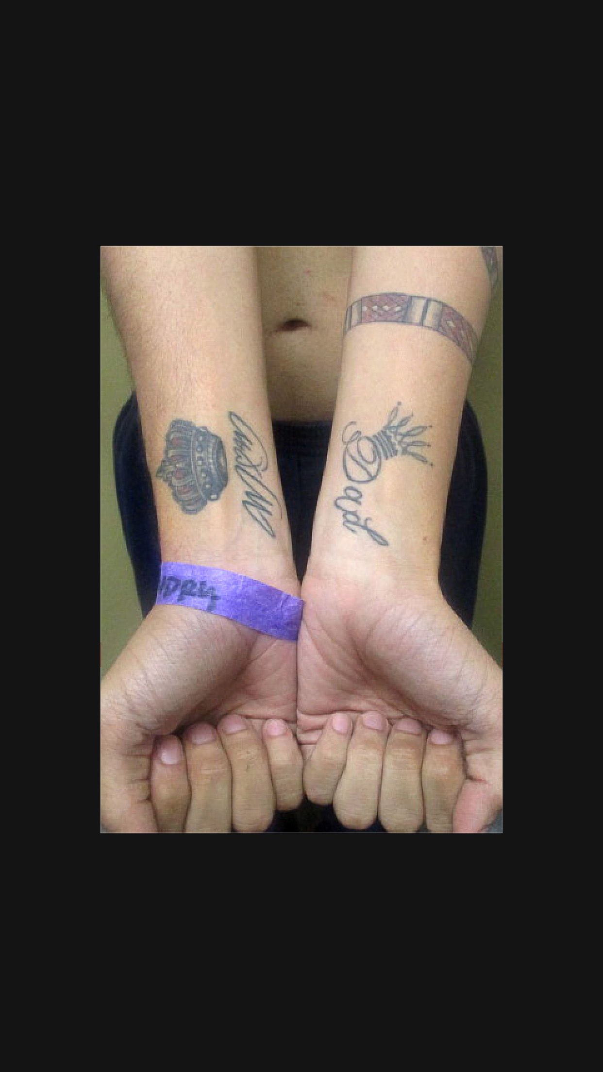 Prisoner holds wrists upwards to show tattoos on forearms of Mom on one arm and Dad on the other, with a crown above each