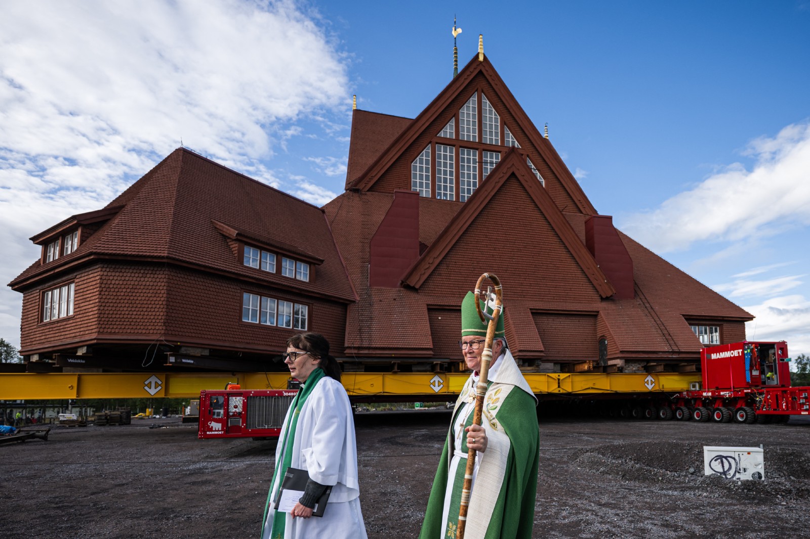 Kiruna vicar Lena Tjarnberg (L) dressed in white robes and green tippet and Bishop of Lulea diocese, Asa Nystrom, in a green robe and mitre carrying a staff can bee seen in front of the church on its transport platform