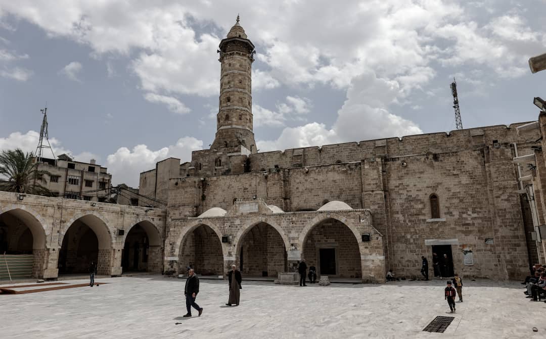 Adult men and boys walk and talk in the courtyard of the Great Omari Mosque in Gaza City, in April 2023