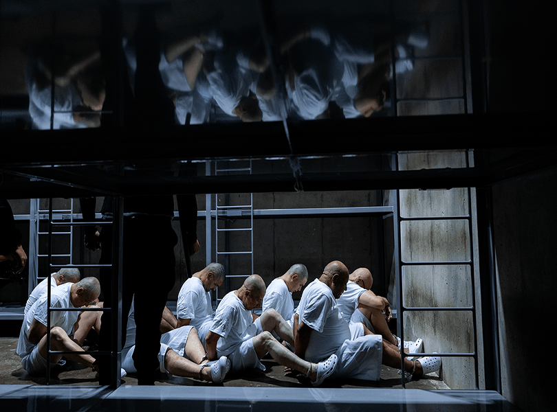 Un grupo de prisioneros del Cecot sentados en fila al interior de una celda