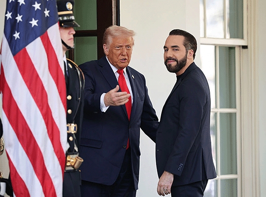 Donald Trump conversa con Nayib Bukele, junto a ellos hay un militar de Estados Unidos y una bandera de ese país