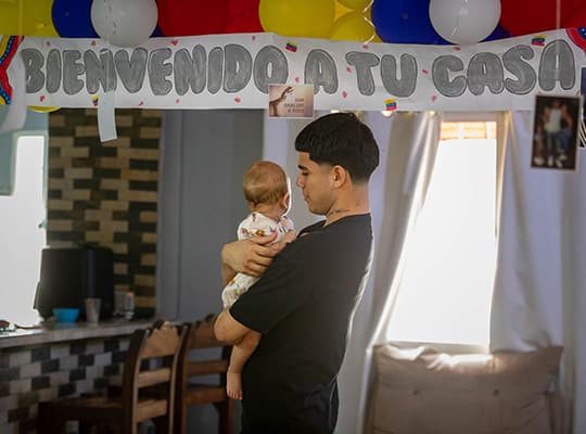 Joén Suárez sostiene en brazos a su hija desde la casa de su familia a las afueras de Caracas. 