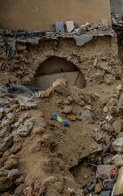 Photo shows the place where was the Hammam a-Samra, inside the medieval gold market, in March 2025. We can see mounts of rubble and sand in the front of the scene and destroyed buildings in the background