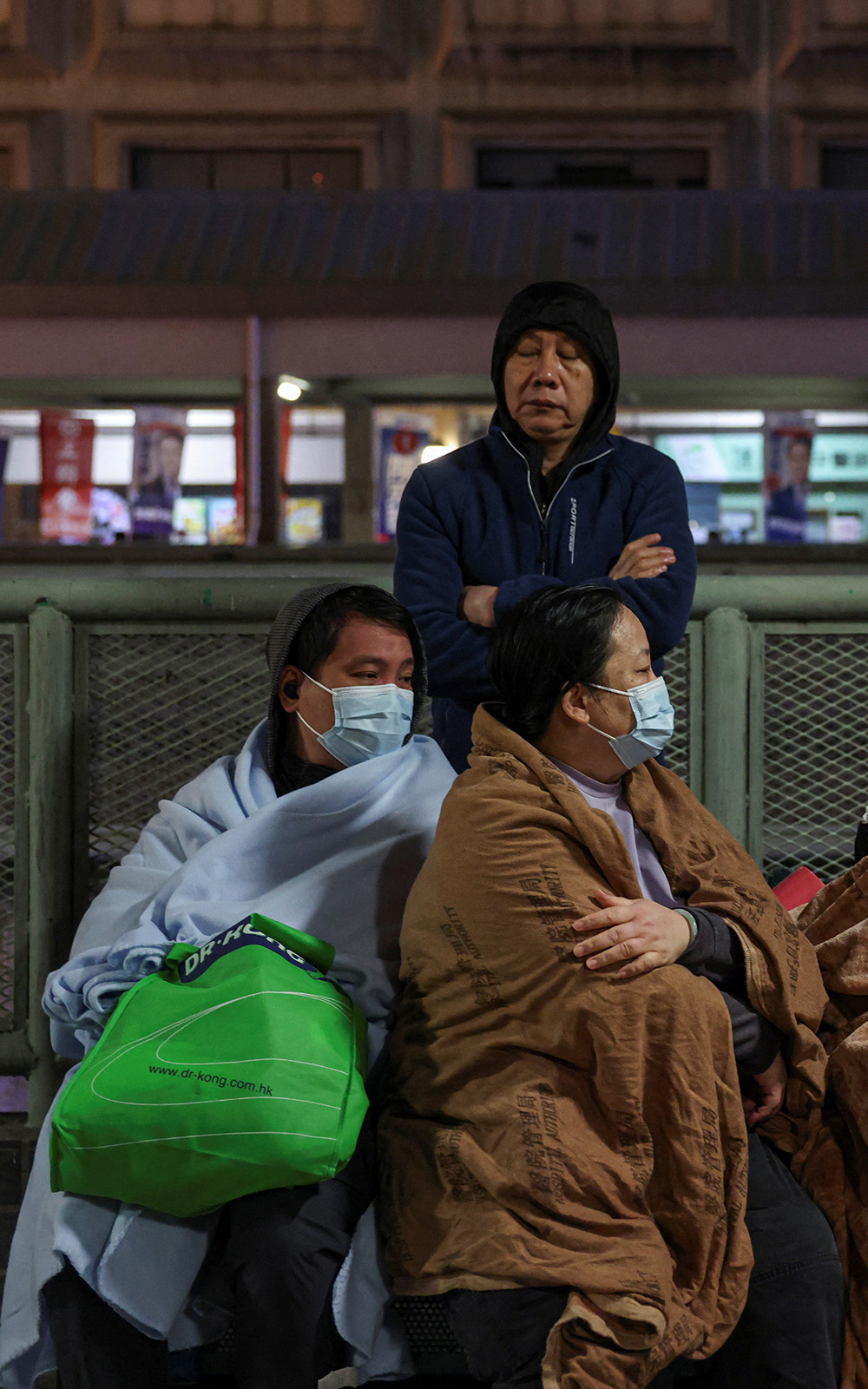 Tower block residents wrapped in blankets wait together 
