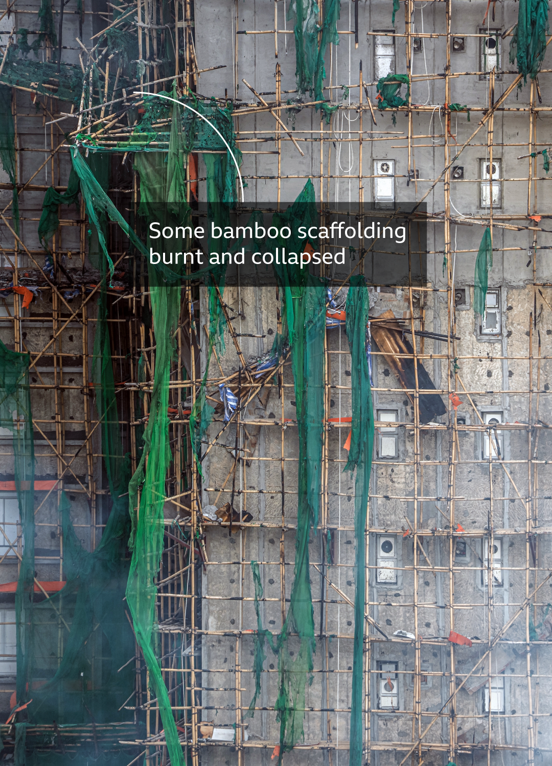 Image shows bamboo scaffolding on the side of a building with melted mesh netting