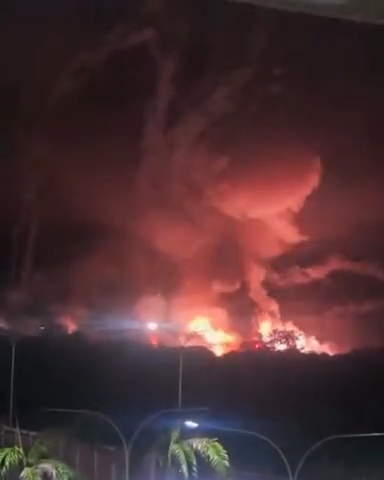 Photos of explosion with flames and trails of smoke in the sky. Palm trees are illuminated by street lamps in the foreground