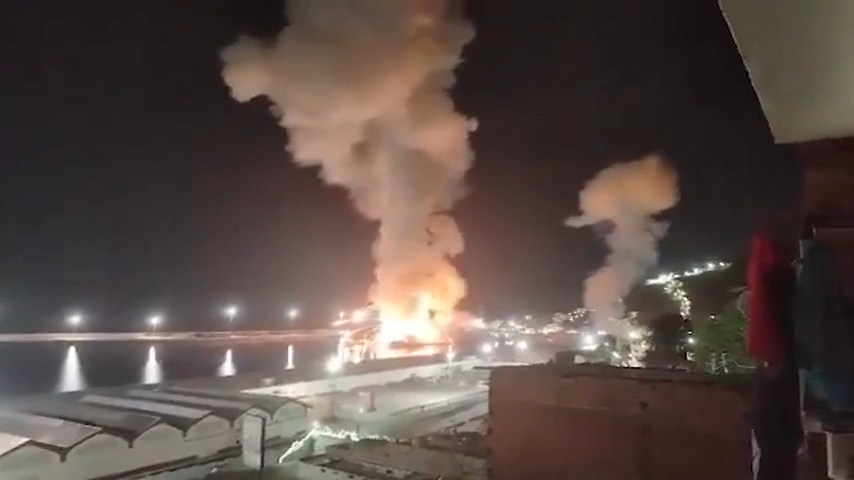 Nighttime scene of port of La Guaira showing a large fire with thick smoke rising into the sky