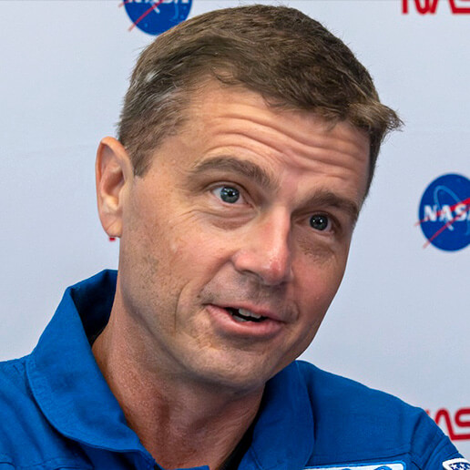 A headshot of Commander Reid Wiseman mid converstion. He is an athletic looking man; white, middle-aged with short, fair hair and blue eyes.