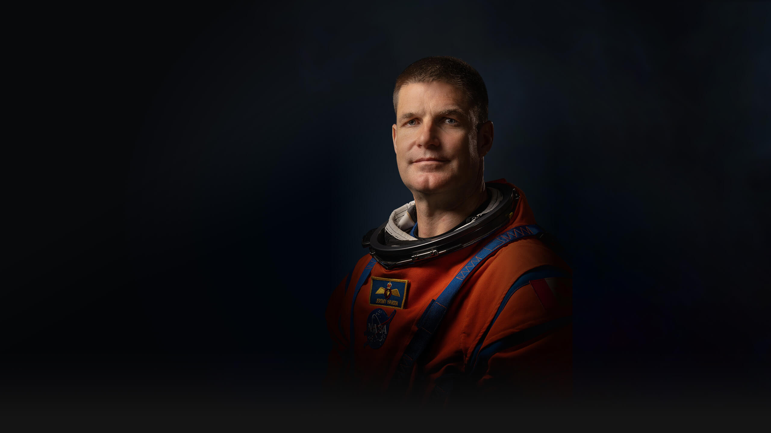 Official Nasa portrait of Jeremy Hansen in his orange spacesuit showing him from mid-waist. With short hair and a cleft chin, he is clearly a big man and, perhaps, looks a little uncomfortable having his photo taken.