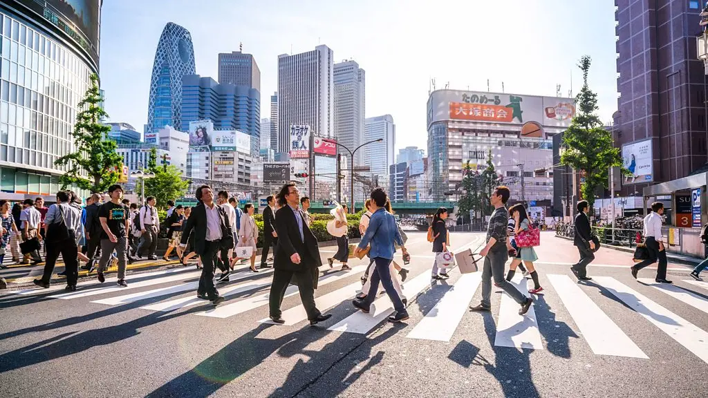 People cross the road on a zebra crossing in a city in Japan, with sky scrapers in the background