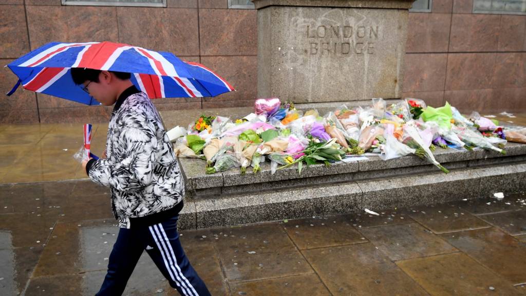 Person walks past flowers on London Bridge