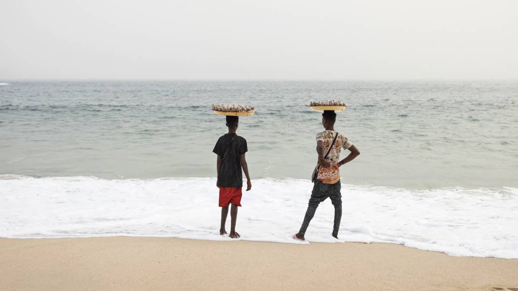 Two people selling food relax at a beach in Lagos, Nigeria - February 2023