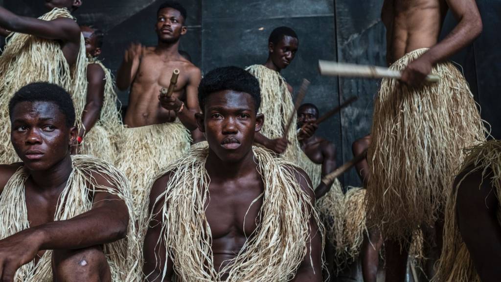 Men dressed in traditional costumes wait to go on stage to perform during a presentation of the 'Capoeira for Peace' project in Kinshasa