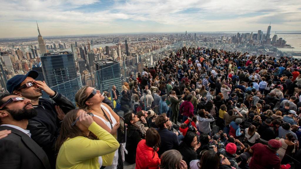 People watch the partial solar eclipse as they gather on the observation deck of Edge at Hudson Yards in New York Cit