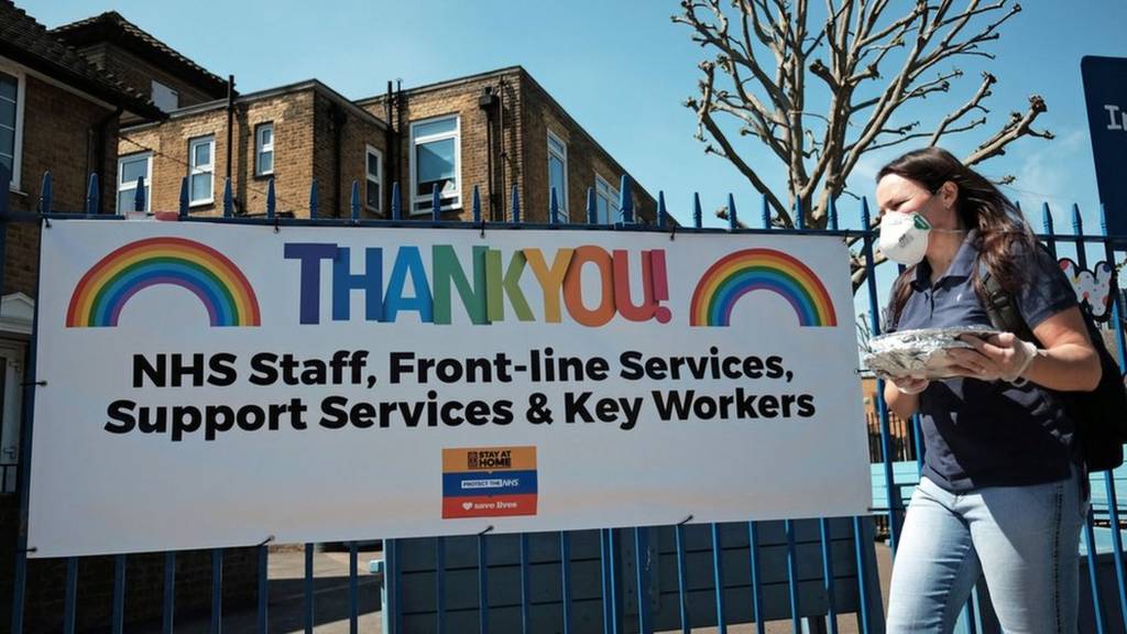 A woman wearing a face mask walking past a "Thank You" to NHS staff and key workers banner on the Isle of Dogs, east London, as the UK continues in lockdown to help curb the spread of the coronavirus.