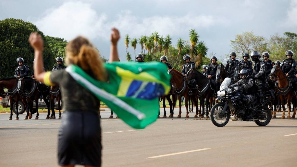 A demonstrator gestures towards members of security forces as supporters of Brazil's former President Jair Bolsonaro leave a camp outside the Army Headquarters, in Brasilia, Brazil, 9 January