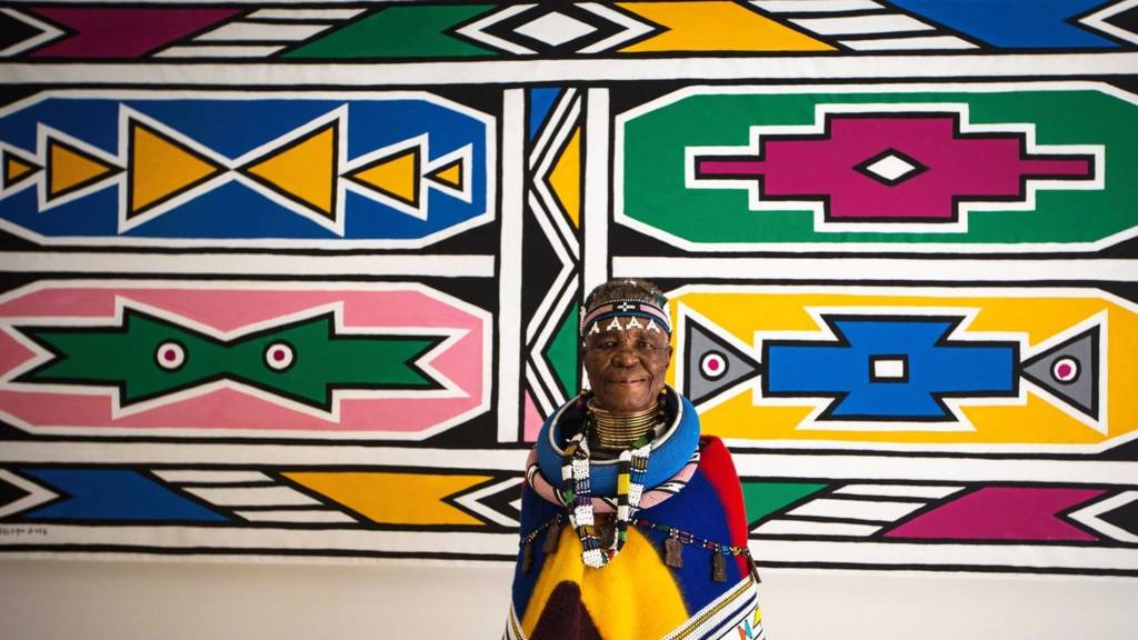 South African artist Esther Mahlangu stands in front of one of her piece